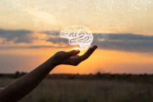 une main ouverte avec au dessus une représentation d'un cerveau lumineux