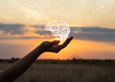 une main ouverte avec au dessus une représentation d'un cerveau lumineux