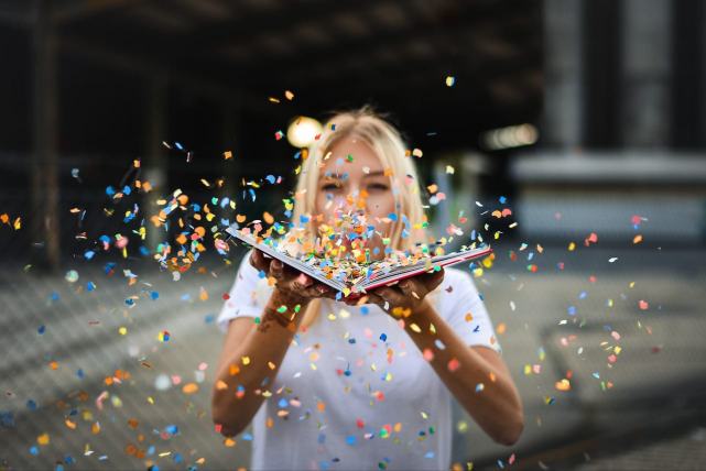 Une femme souffle sur des confettis s'envolant d'un livre ouvert