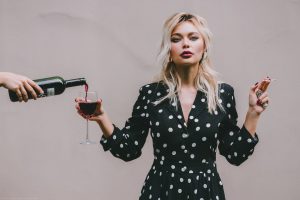Une femme tenant un verre de vin à la main droite et une cigarette à l'autre main
