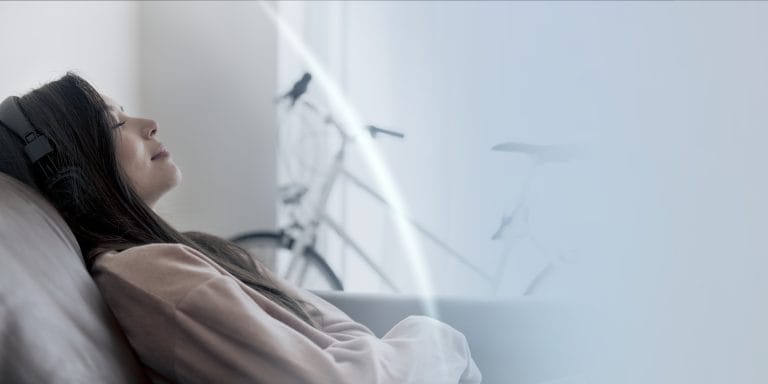 Femme allongée paisiblement dans son lit, en pleine séance d’auto-hypnose avant de dormir